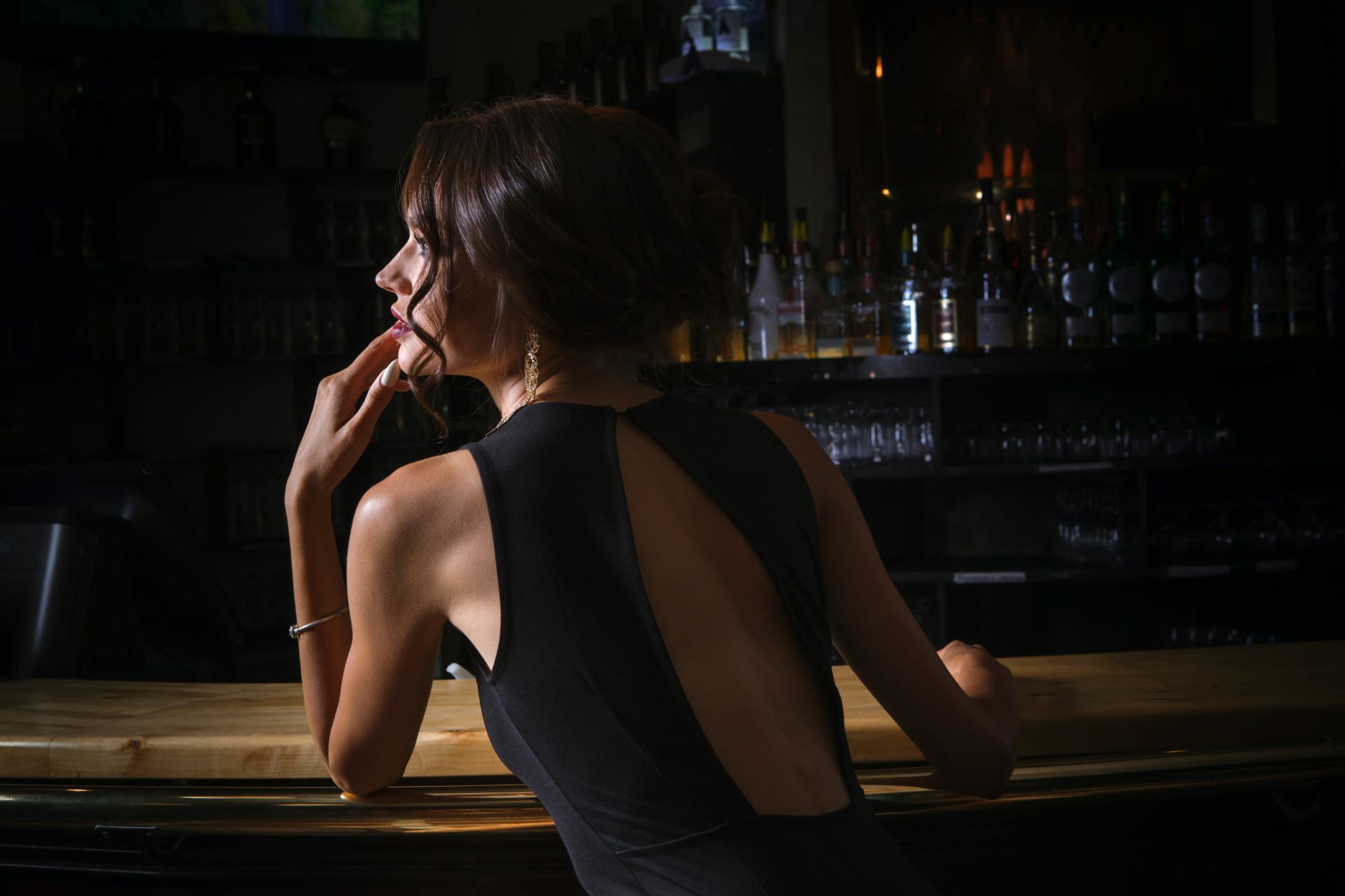 Elegante Frau in schwarzem Kleid an einer Bar, repräsentiert stilvolle Abendbegleitung und VIP Escort Service